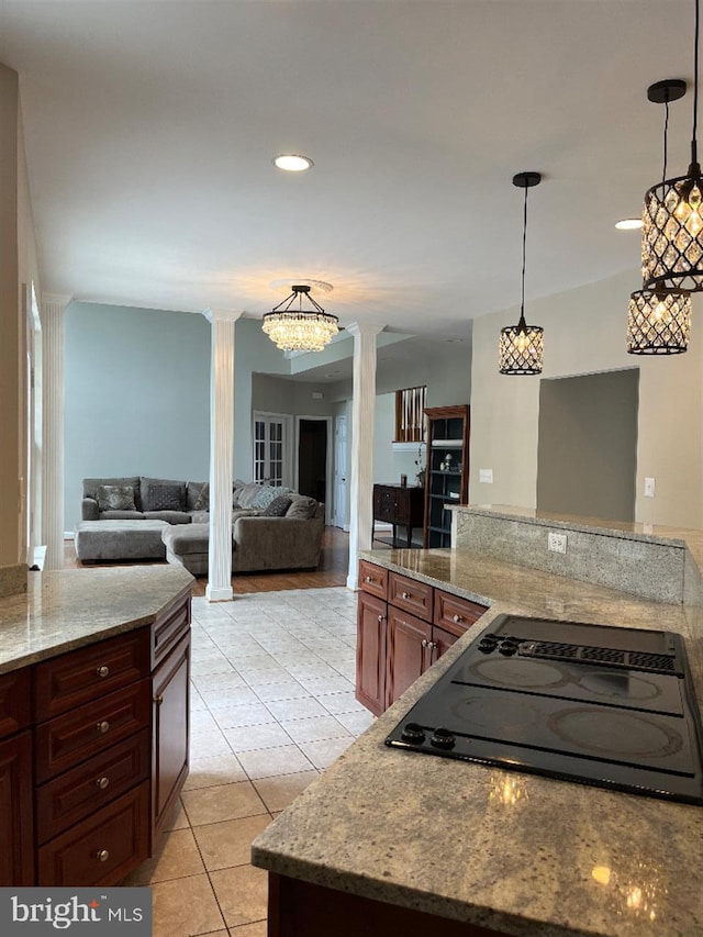 kitchen with light stone countertops, light tile patterned floors, pendant lighting, and decorative columns