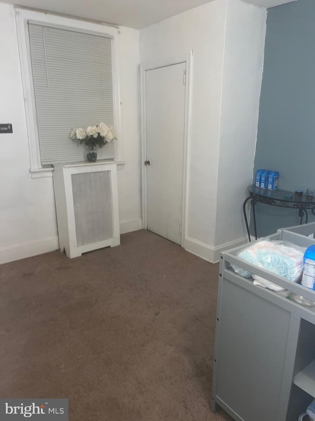 laundry area with radiator and dark colored carpet