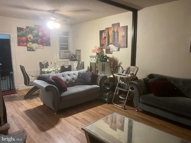 living room with ceiling fan, wood-type flooring, and a textured ceiling