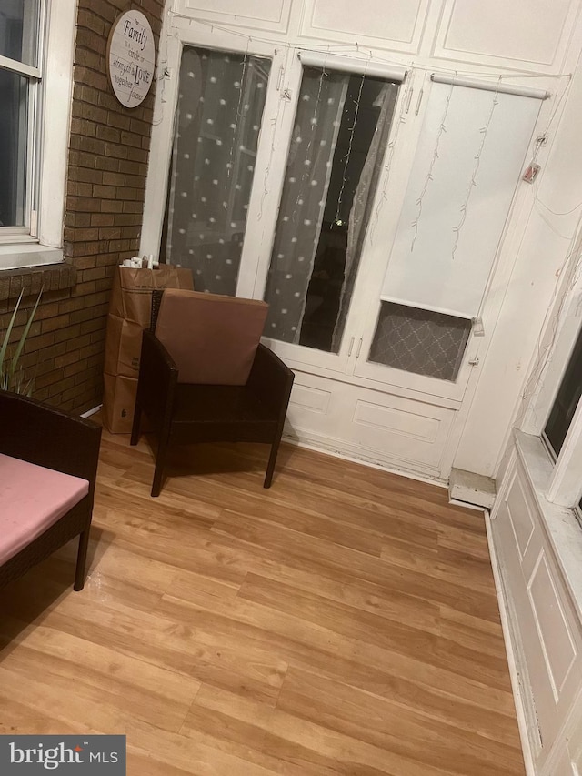 sitting room featuring brick wall and light wood-type flooring