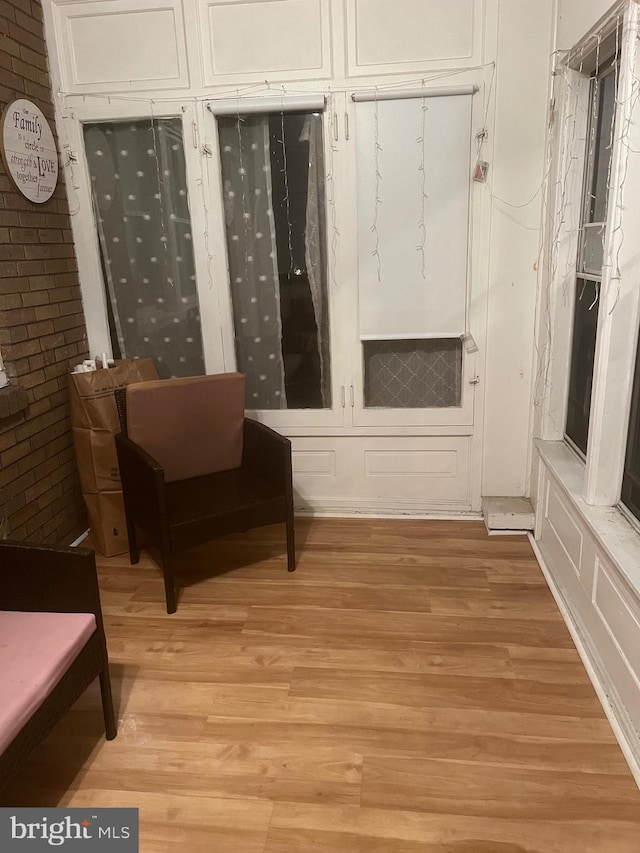 sitting room featuring brick wall and light hardwood / wood-style flooring