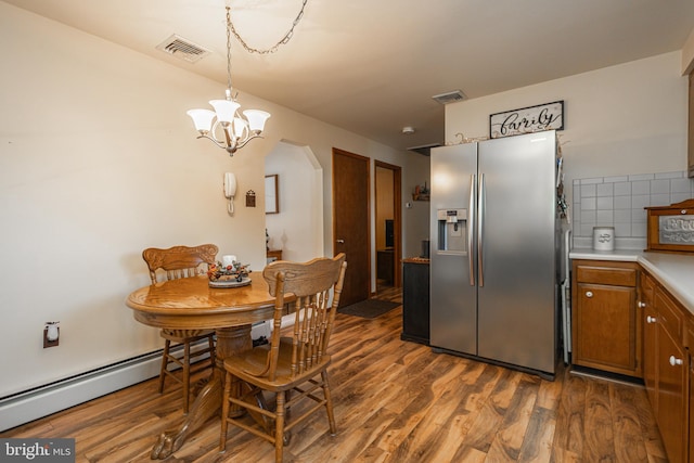 dining space with a baseboard radiator, a notable chandelier, and dark hardwood / wood-style flooring