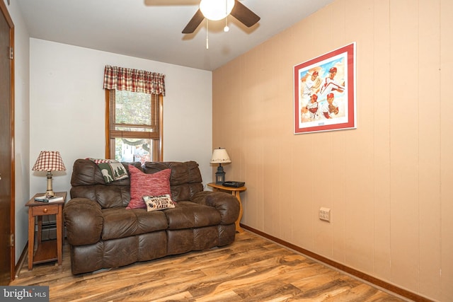 living room featuring wood walls, wood-type flooring, and ceiling fan