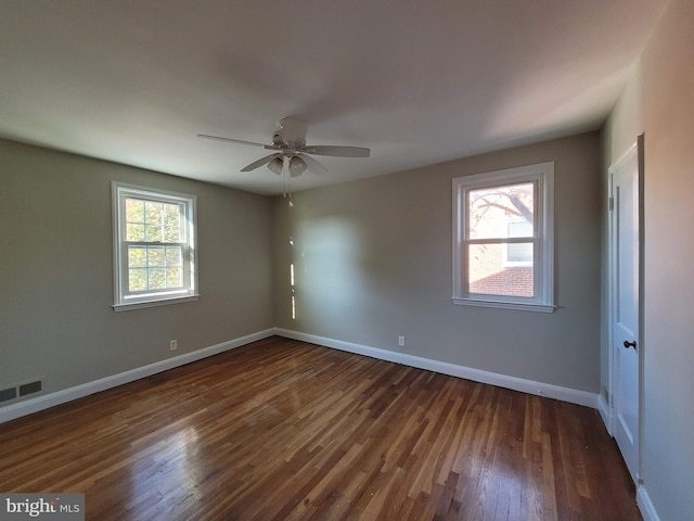 empty room with dark hardwood / wood-style floors, plenty of natural light, and ceiling fan