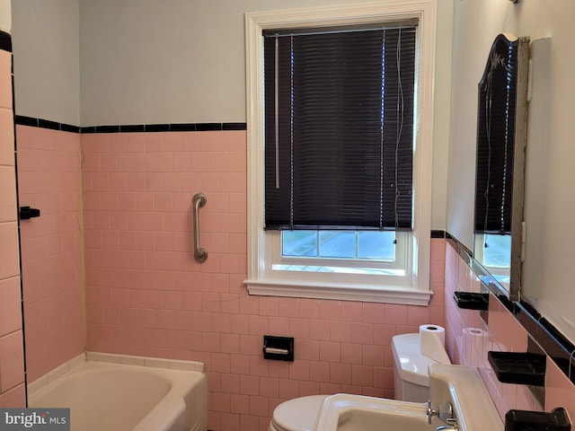 bathroom with toilet, tile walls, and a tub