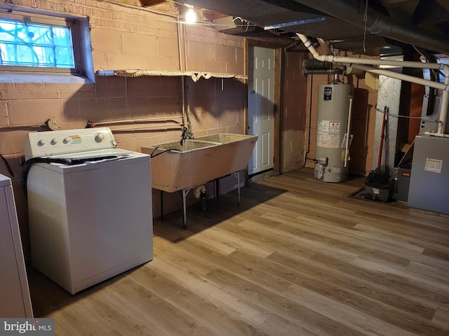 clothes washing area with washer / dryer, light wood-type flooring, sink, and water heater