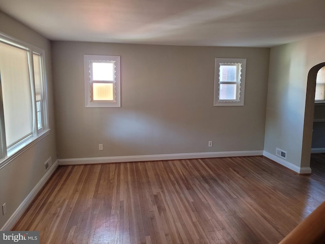 spare room with a wealth of natural light and dark wood-type flooring