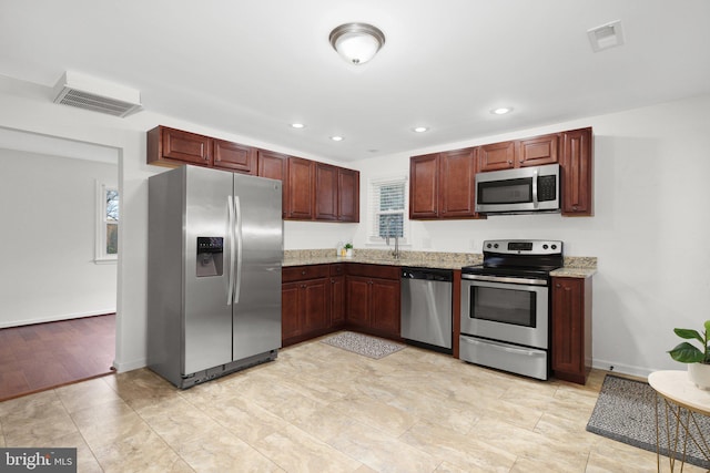 kitchen with light stone counters, light wood-type flooring, and appliances with stainless steel finishes