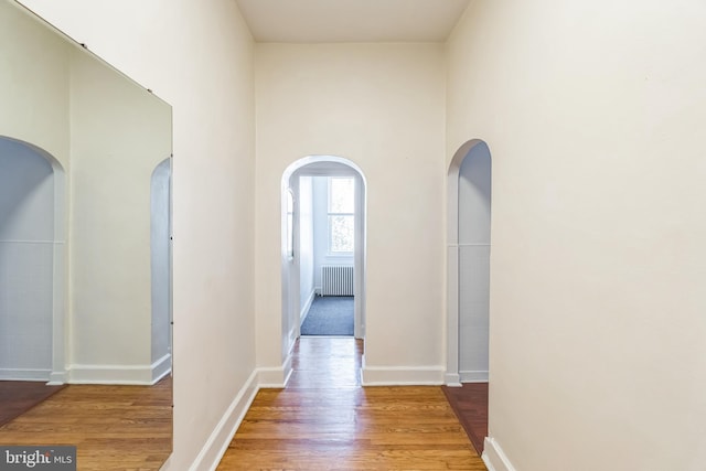 corridor with radiator heating unit and light wood-type flooring