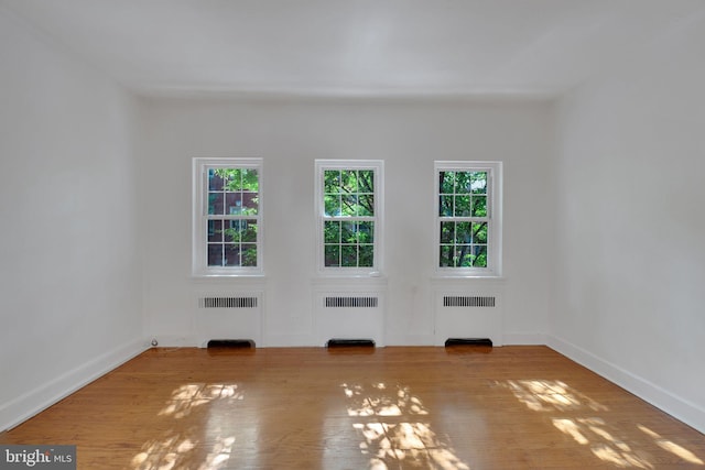 unfurnished living room with hardwood / wood-style flooring and radiator