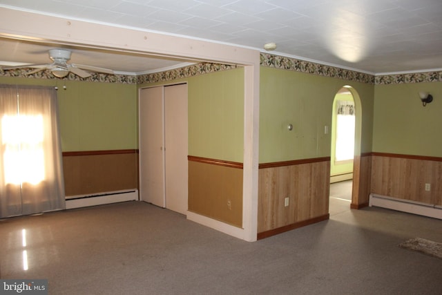 unfurnished room featuring ceiling fan, wood walls, and baseboard heating