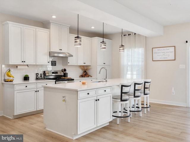 kitchen featuring a center island with sink, electric stove, decorative light fixtures, light hardwood / wood-style floors, and white cabinetry