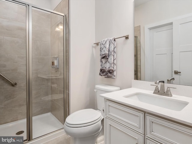 bathroom with vanity, toilet, and a shower with door