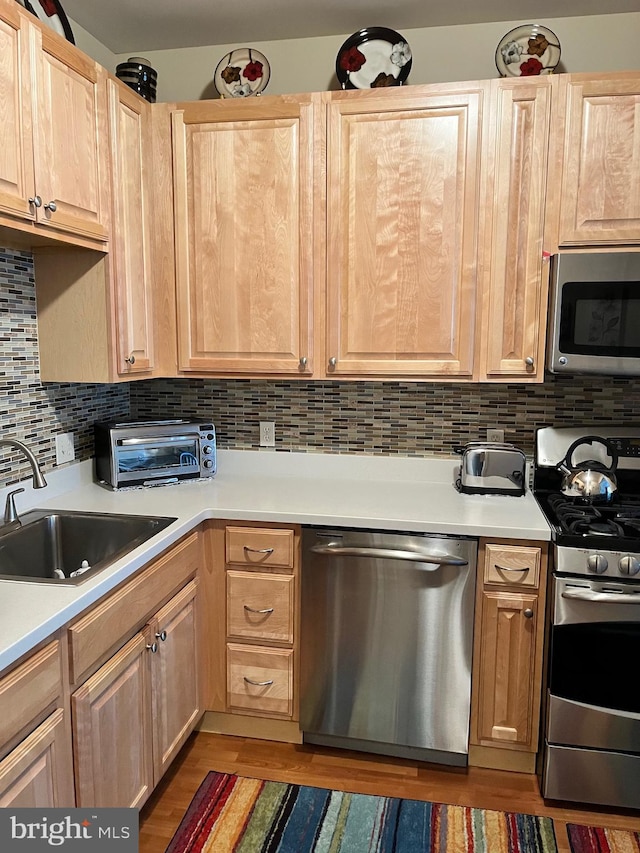 kitchen featuring stainless steel appliances, tasteful backsplash, sink, and light brown cabinets