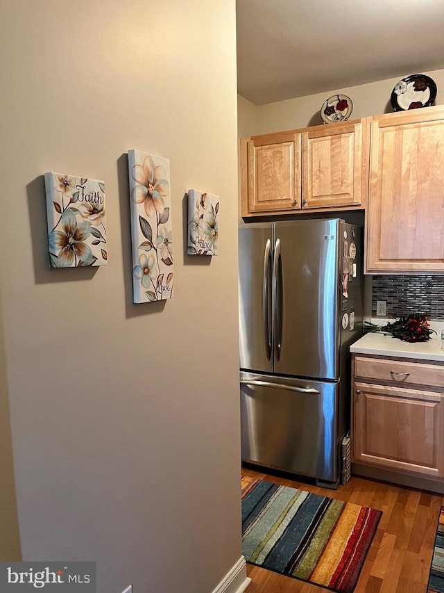 kitchen featuring stainless steel refrigerator, light hardwood / wood-style floors, tasteful backsplash, and light brown cabinets