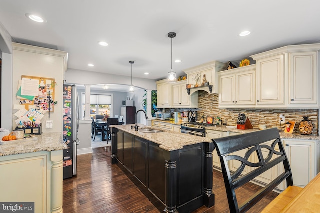 kitchen featuring cream cabinetry, dark wood-type flooring, sink, pendant lighting, and light stone counters