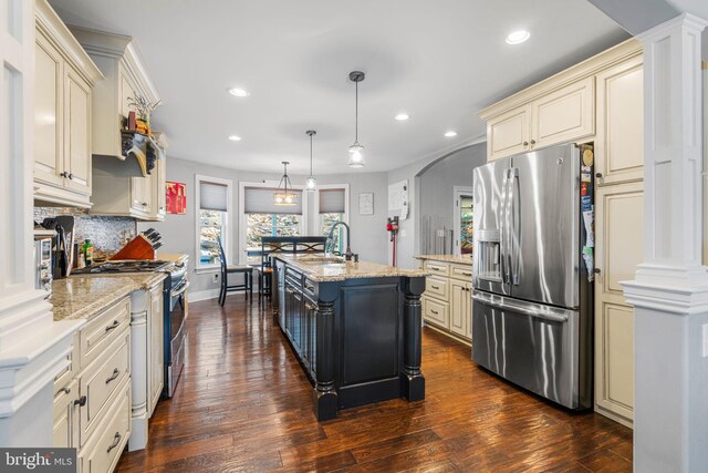 kitchen with stainless steel appliances, dark hardwood / wood-style flooring, pendant lighting, and a center island with sink