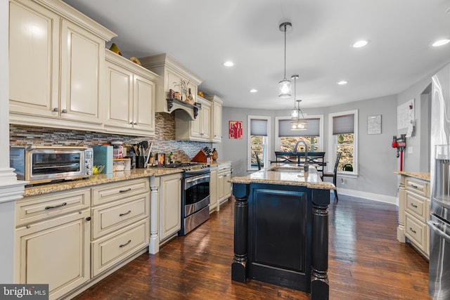 kitchen featuring a kitchen island, cream cabinets, stainless steel range, pendant lighting, and dark hardwood / wood-style flooring