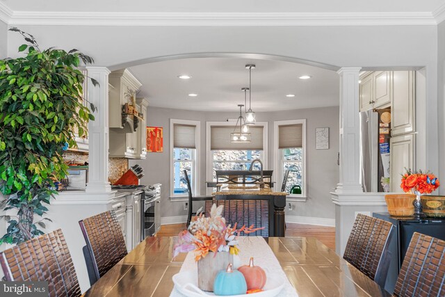 dining room with ornamental molding, light hardwood / wood-style floors, and a healthy amount of sunlight