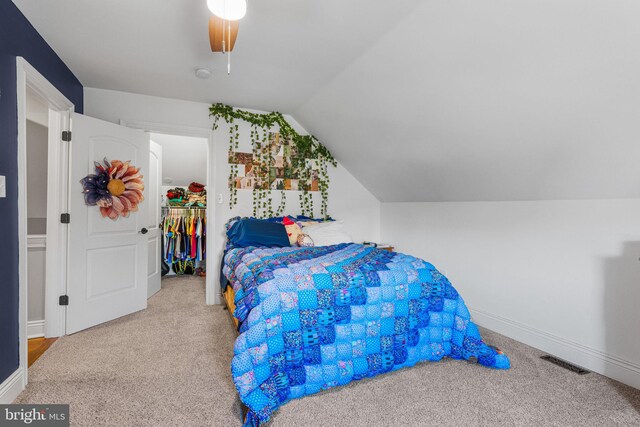 carpeted bedroom with a closet, ceiling fan, lofted ceiling, and a walk in closet