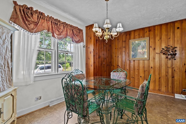 dining area with a notable chandelier, wood walls, and a textured ceiling