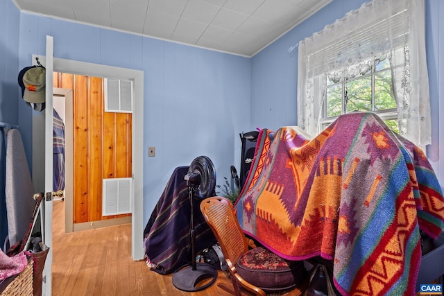 bedroom featuring crown molding, wood walls, and light wood-type flooring