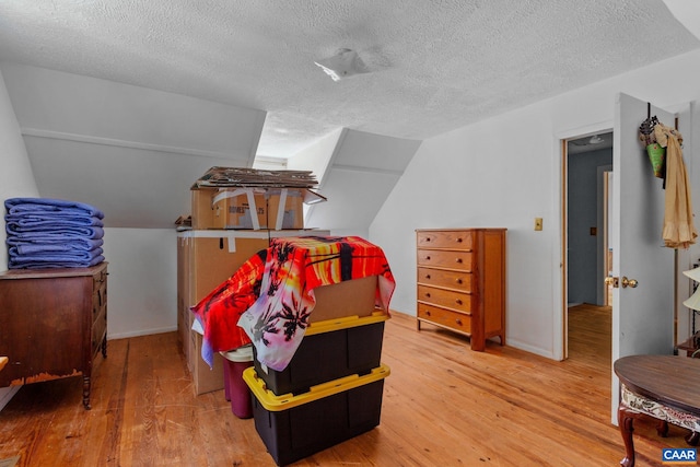 bedroom with a textured ceiling, hardwood / wood-style flooring, and vaulted ceiling