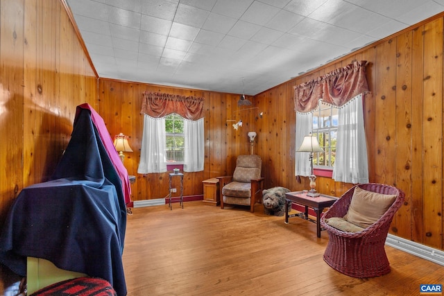 sitting room featuring wood walls, wood-type flooring, and ornamental molding