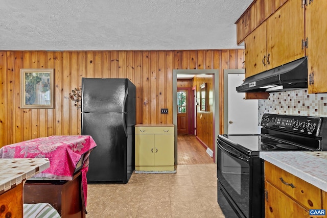 kitchen with wood walls, tasteful backsplash, black appliances, and a textured ceiling