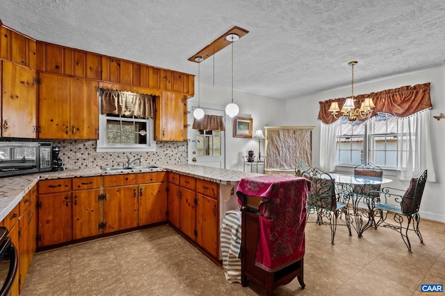 kitchen featuring plenty of natural light, decorative backsplash, decorative light fixtures, and black appliances