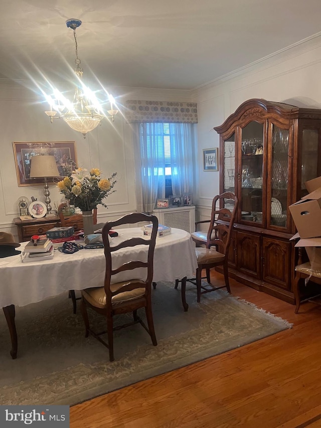 dining area with ornamental molding, a notable chandelier, and hardwood / wood-style floors