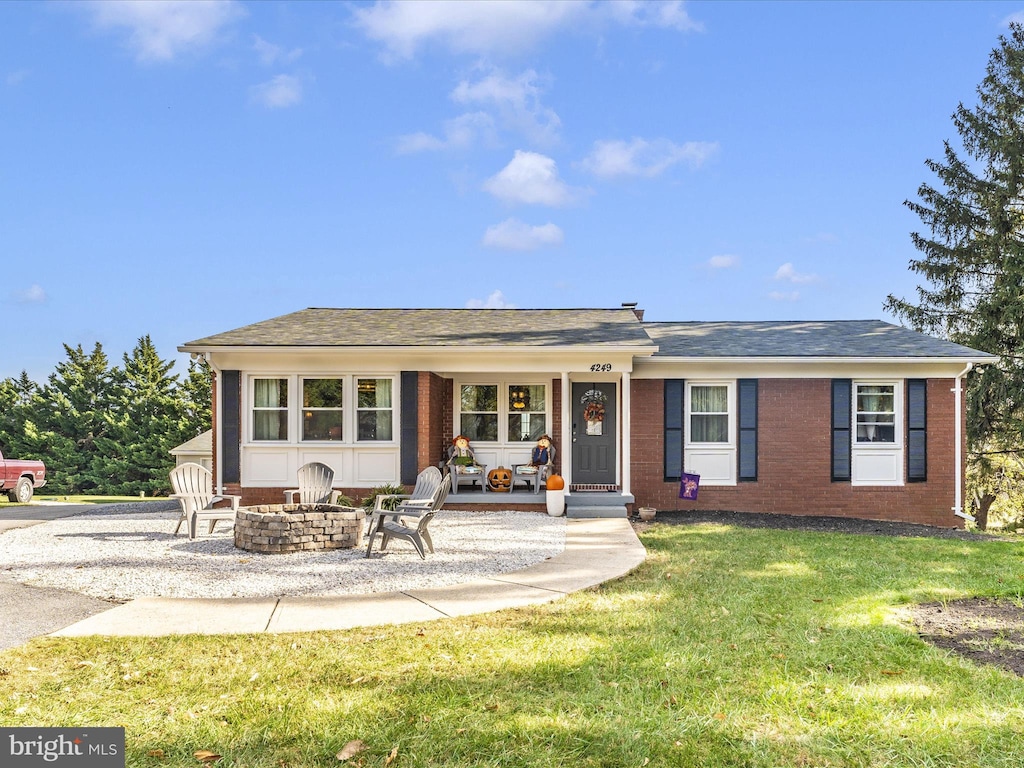 view of front of home with an outdoor fire pit and a front lawn