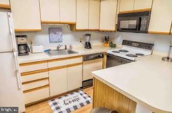 kitchen featuring white appliances, light countertops, and a sink