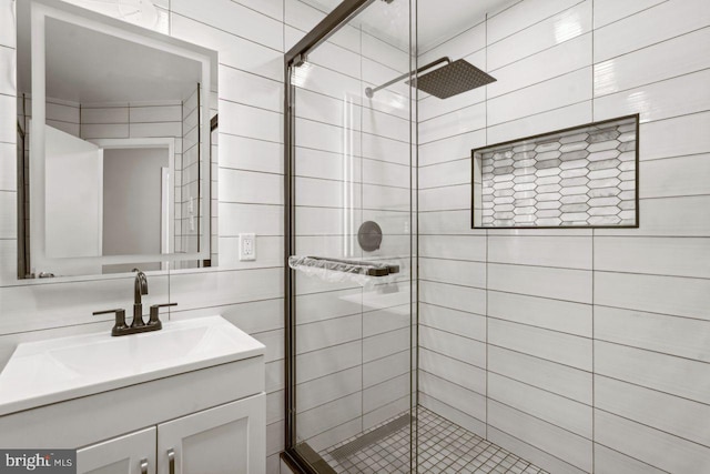 bathroom with tile walls, vanity, and a shower with shower door