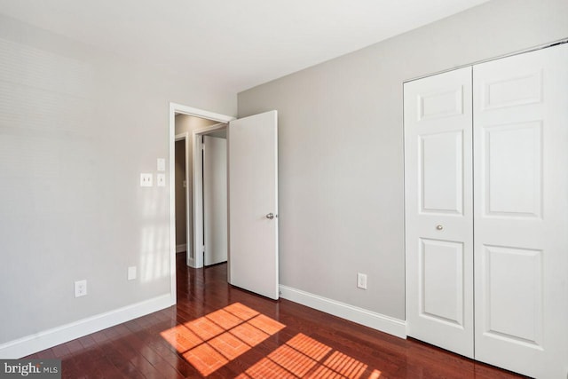 unfurnished bedroom with dark hardwood / wood-style floors and a closet