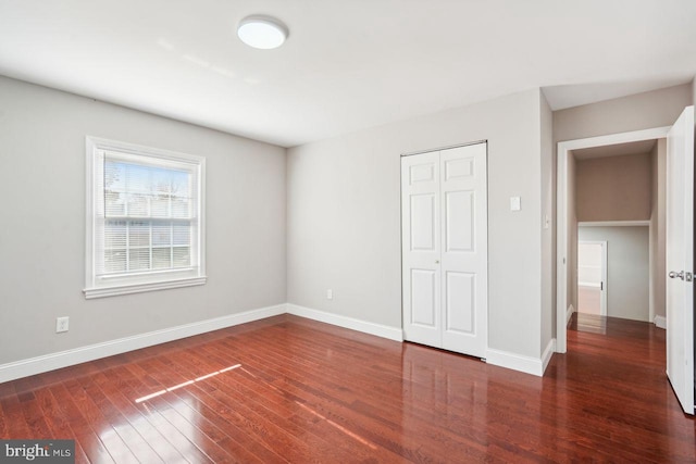 unfurnished bedroom featuring a closet and dark hardwood / wood-style flooring