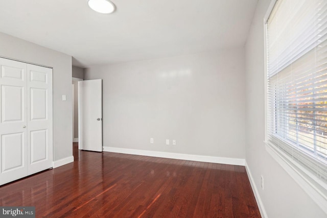 unfurnished bedroom with dark wood-type flooring and a closet