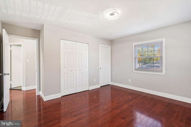 unfurnished bedroom with dark wood-type flooring and a closet