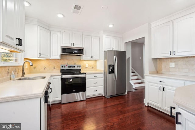 kitchen with stainless steel appliances, white cabinetry, sink, and dark hardwood / wood-style flooring