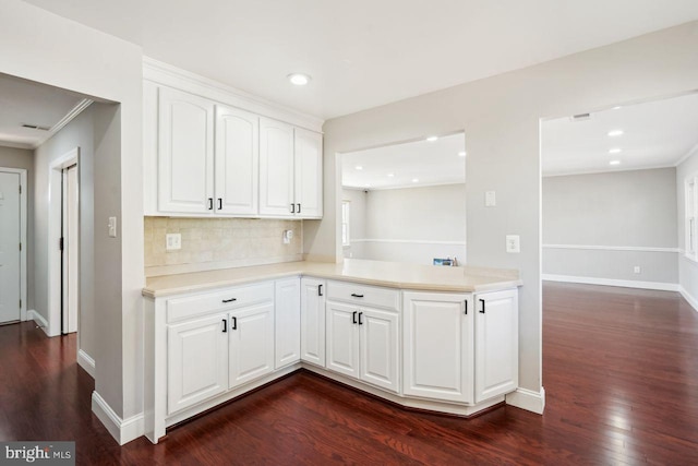 kitchen with dark wood-type flooring, tasteful backsplash, ornamental molding, and white cabinets