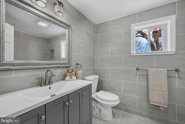 bathroom featuring vanity, toilet, and tile walls