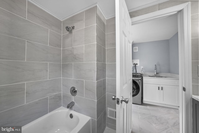 bathroom featuring tiled shower / bath, vanity, and washer / clothes dryer