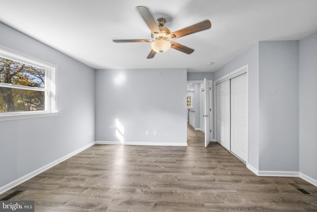 unfurnished bedroom with a closet, ceiling fan, and dark hardwood / wood-style flooring