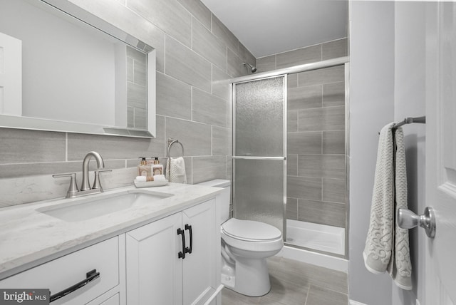 bathroom with vanity, toilet, tile walls, and an enclosed shower