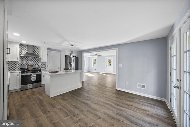 kitchen featuring a center island with sink, white cabinetry, stainless steel appliances, and wall chimney exhaust hood