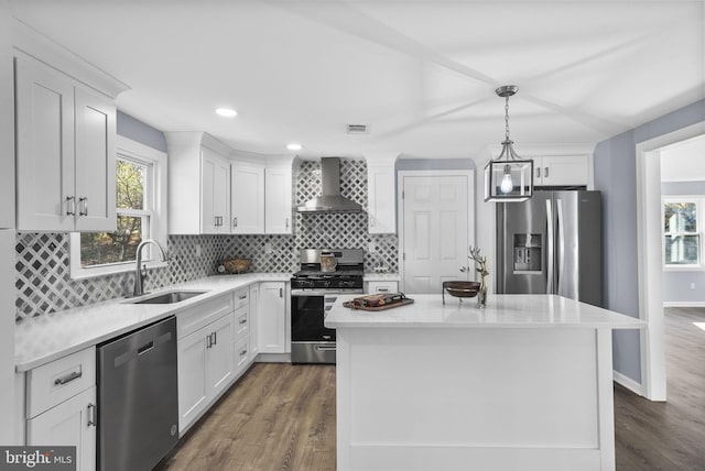 kitchen with a kitchen island, wall chimney exhaust hood, stainless steel appliances, sink, and white cabinetry