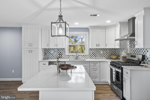 kitchen featuring wall chimney exhaust hood, dark wood-type flooring, sink, stainless steel gas range oven, and white cabinets