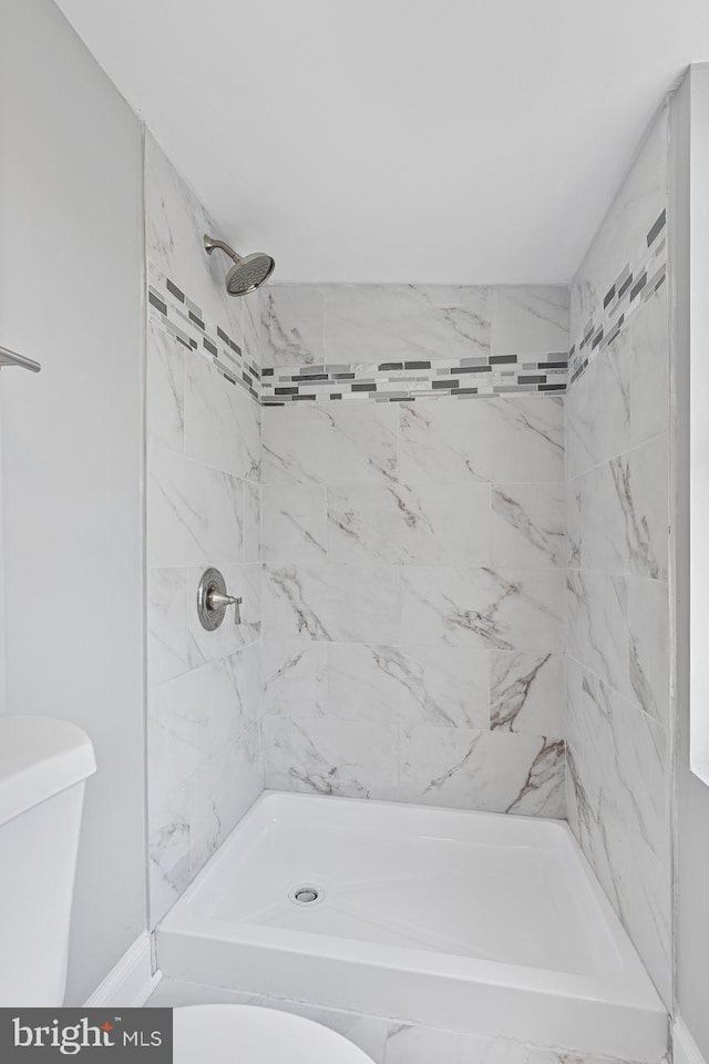 bathroom with tiled shower and toilet