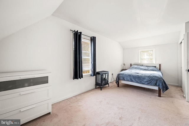 bedroom with a wood stove, lofted ceiling, and light colored carpet