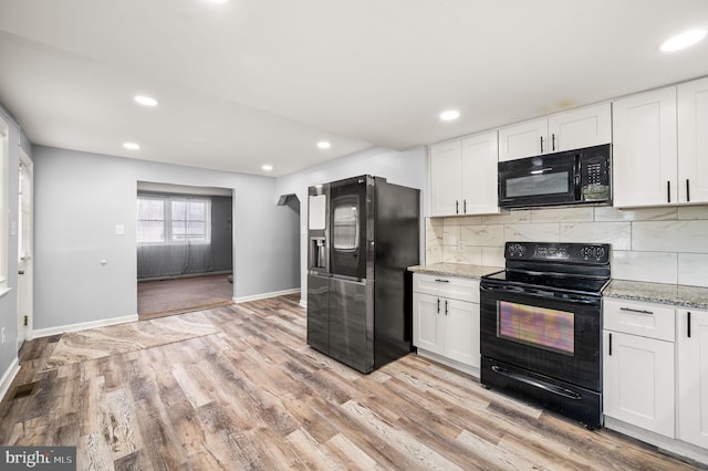 kitchen featuring black appliances, white cabinetry, light stone counters, and light wood-type flooring